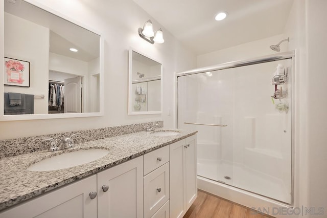 bathroom with hardwood / wood-style flooring, a shower with shower door, and vanity