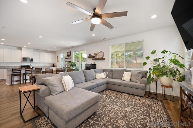 living room featuring ceiling fan and dark hardwood / wood-style floors