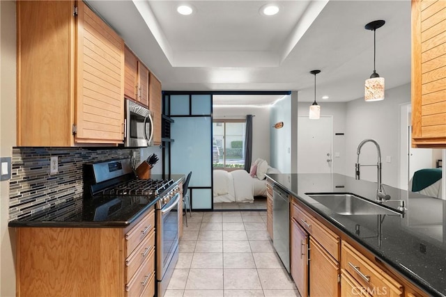 kitchen featuring dark stone countertops, hanging light fixtures, stainless steel appliances, and sink