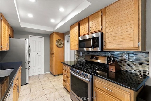 kitchen featuring sink, stainless steel appliances, a raised ceiling, decorative backsplash, and light tile patterned floors