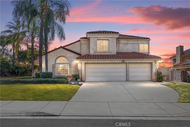 mediterranean / spanish house featuring a garage and a lawn