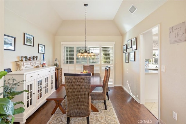 dining space featuring vaulted ceiling, a chandelier, and wood-type flooring