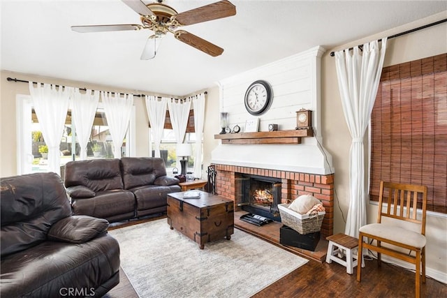 living room featuring ceiling fan, dark hardwood / wood-style floors, and a brick fireplace