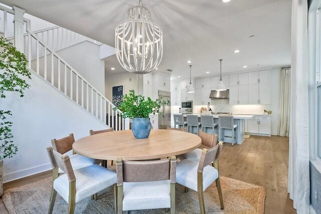 dining space with sink, light hardwood / wood-style flooring, and a notable chandelier