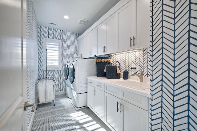 clothes washing area featuring cabinets, separate washer and dryer, and sink