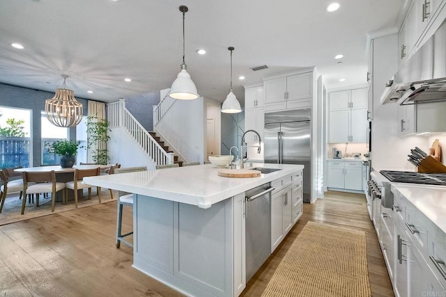 kitchen with pendant lighting, white cabinetry, a kitchen island with sink, and sink