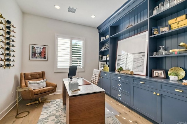 office area with built in features and light wood-type flooring