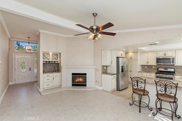 kitchen featuring ceiling fan, stainless steel appliances, a kitchen breakfast bar, stone countertops, and decorative backsplash