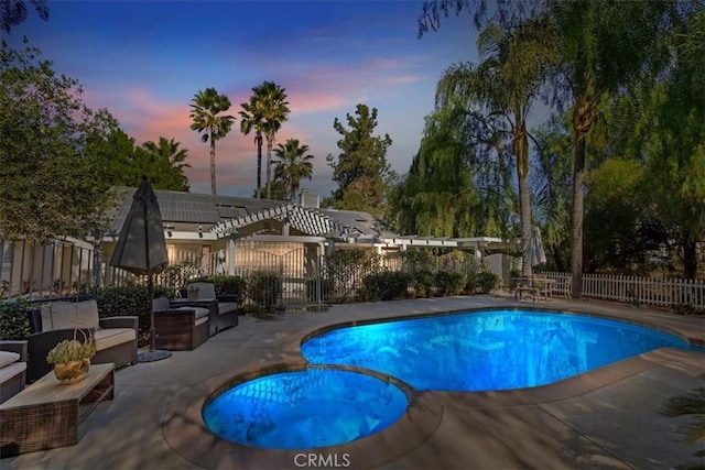 pool at dusk with an in ground hot tub and a patio