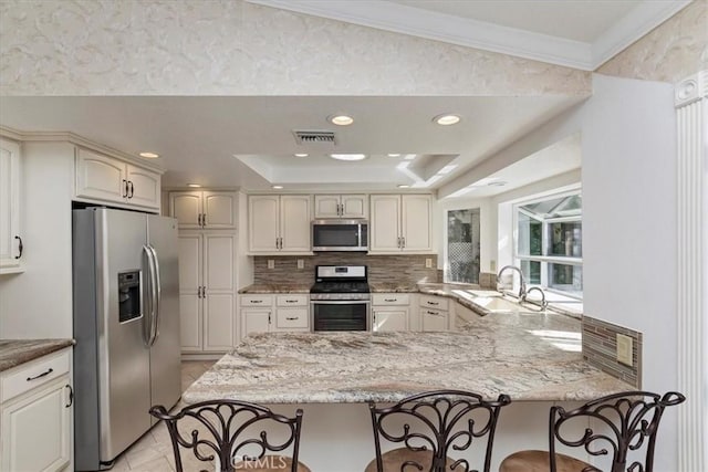 kitchen featuring a kitchen breakfast bar, kitchen peninsula, sink, and appliances with stainless steel finishes