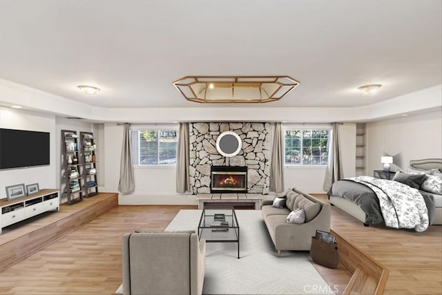 bedroom featuring hardwood / wood-style flooring, a stone fireplace, and multiple windows