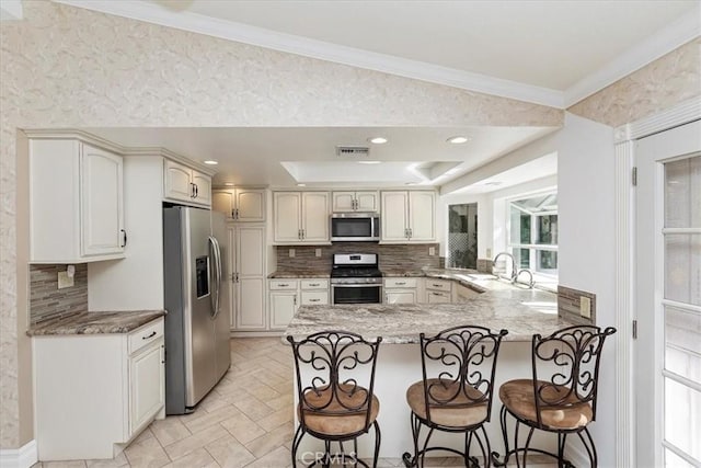 kitchen with a breakfast bar area, kitchen peninsula, tasteful backsplash, and appliances with stainless steel finishes