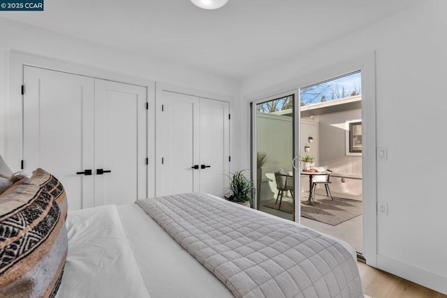 bedroom with two closets, light wood-type flooring, and access to outside