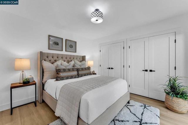 bedroom featuring multiple closets and light hardwood / wood-style floors