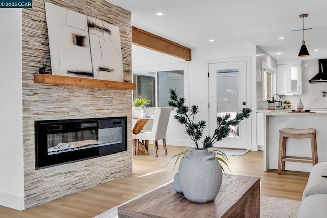 living room featuring a tile fireplace, light wood-type flooring, and sink