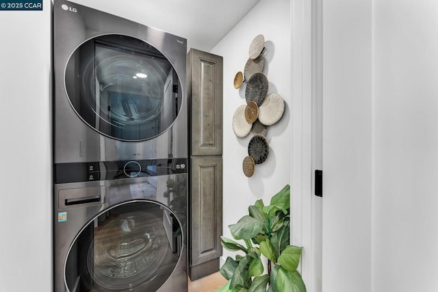 washroom with stacked washing maching and dryer and cabinets