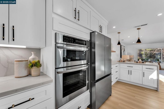 kitchen with decorative light fixtures, stainless steel appliances, backsplash, and white cabinetry