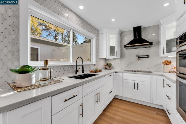 kitchen featuring light stone counters, white cabinets, extractor fan, and sink