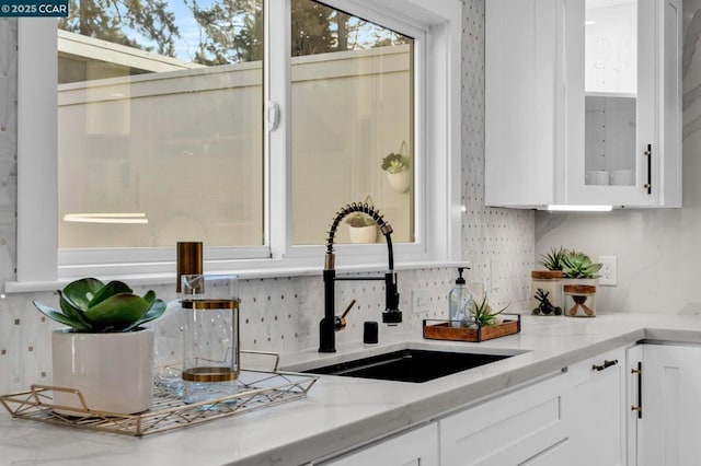 kitchen featuring sink, white cabinets, and light stone counters