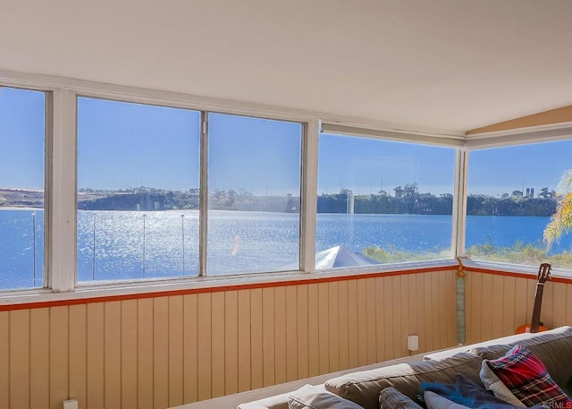 unfurnished sunroom featuring vaulted ceiling and a water view