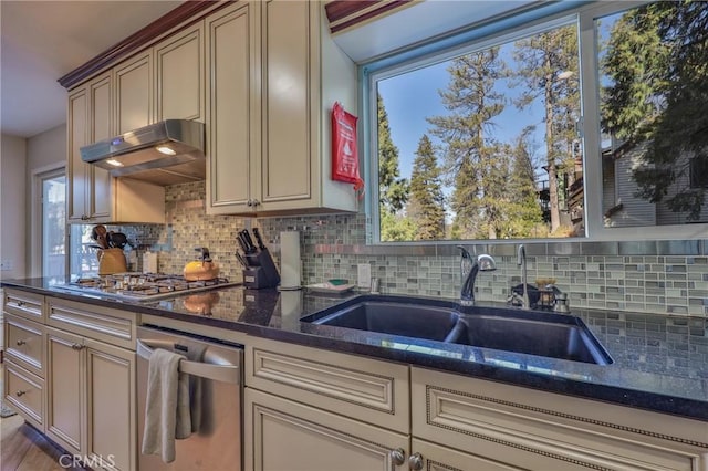 kitchen with dark stone countertops, sink, backsplash, cream cabinets, and stainless steel gas stovetop