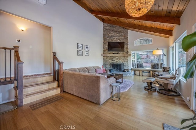 living room featuring wooden ceiling, beam ceiling, and a stone fireplace