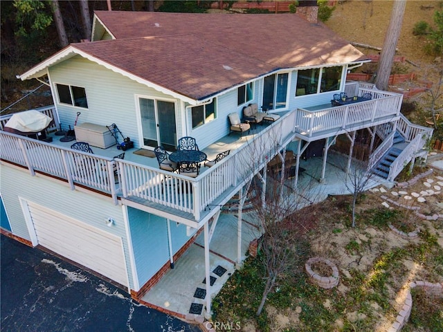 rear view of house with a wooden deck and a jacuzzi