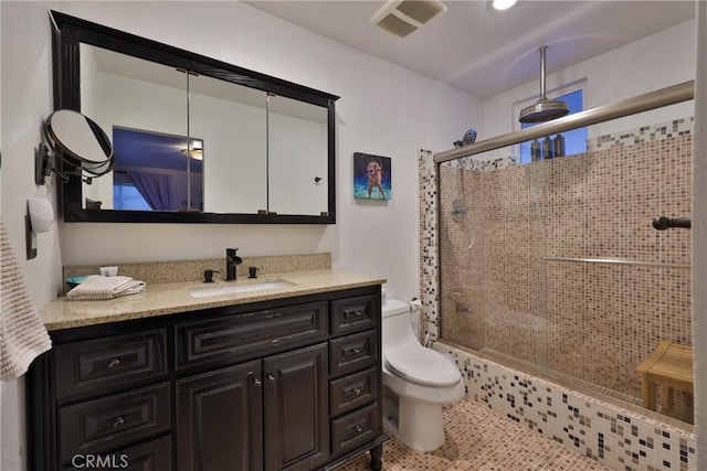 bathroom with a shower with door, toilet, vanity, and tile patterned flooring