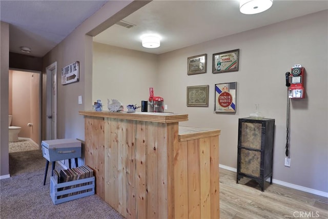 bar with hardwood / wood-style floors and light brown cabinets