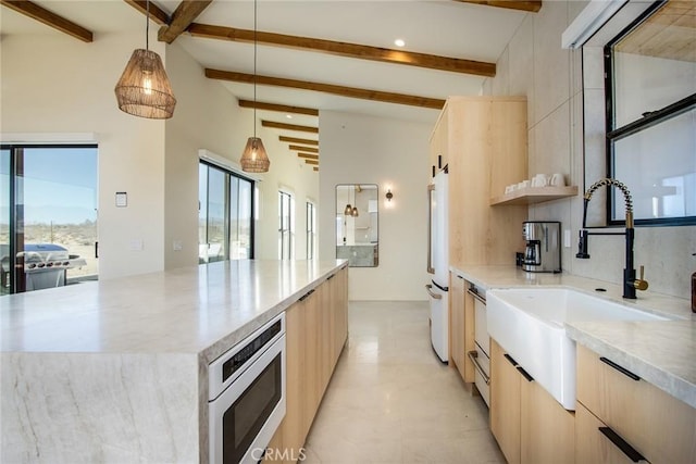 kitchen with stainless steel microwave, decorative light fixtures, beam ceiling, sink, and a large island