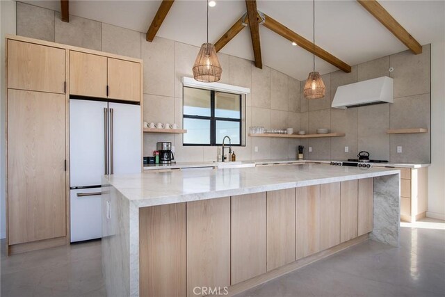 kitchen with light stone countertops, extractor fan, a kitchen island, and high end white fridge