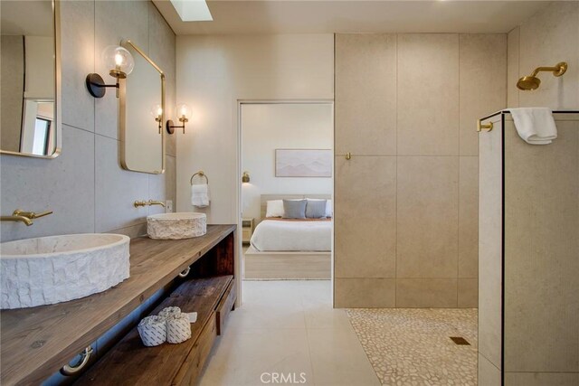 bathroom with tiled shower, vanity, a skylight, and tile patterned flooring