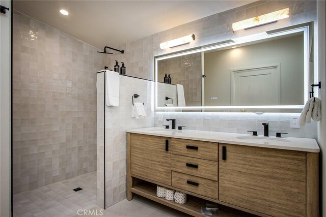 bathroom with vanity, a tile shower, tile walls, and backsplash