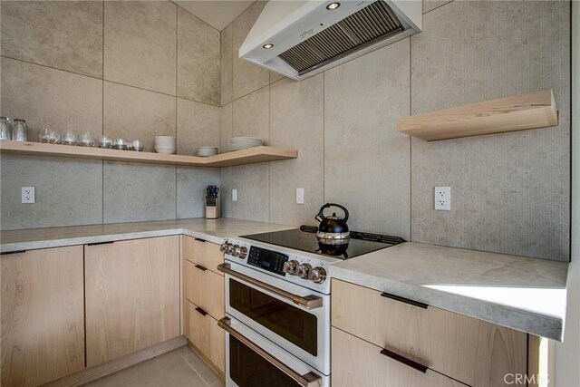 kitchen with wall chimney exhaust hood, double oven range, and light brown cabinetry