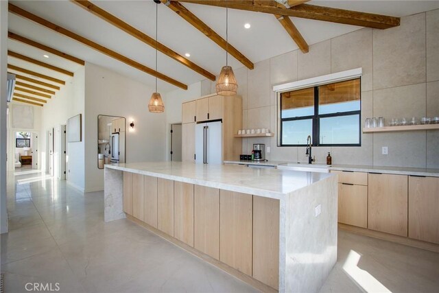 kitchen with light stone counters, high end refrigerator, a center island, light brown cabinets, and pendant lighting