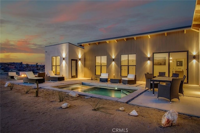 back house at dusk featuring a patio area