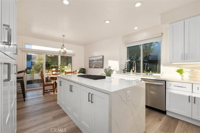 kitchen featuring stainless steel dishwasher, light wood-style flooring, white cabinetry, and a kitchen island