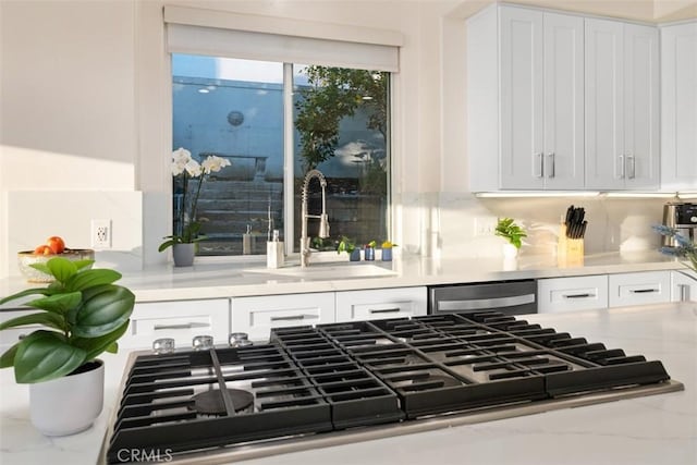 interior space featuring sink, white cabinetry, light stone counters, gas cooktop, and dishwasher