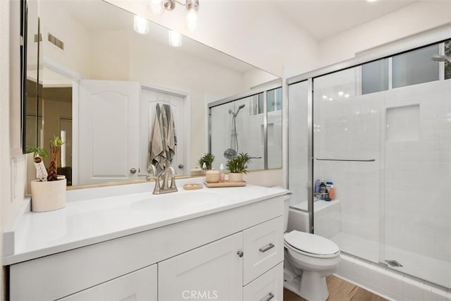 bathroom with vanity, toilet, a shower with door, and hardwood / wood-style floors