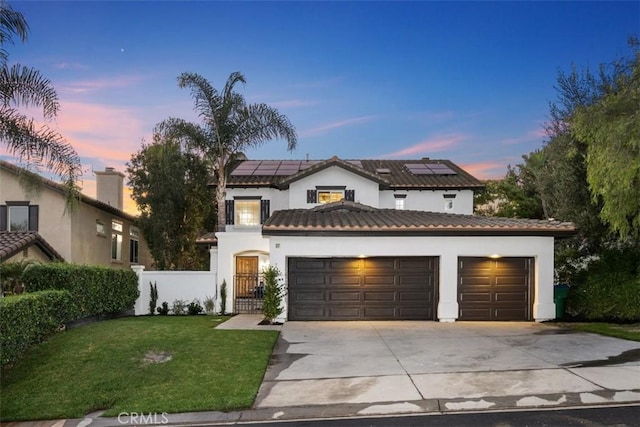 view of front of home featuring roof mounted solar panels, fence, concrete driveway, a front yard, and a garage