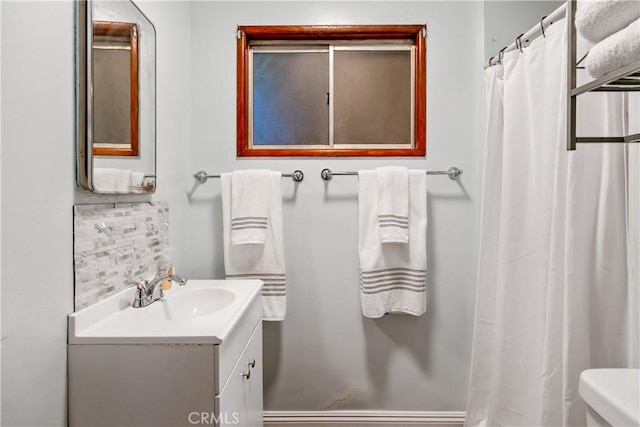 bathroom featuring vanity, backsplash, and toilet