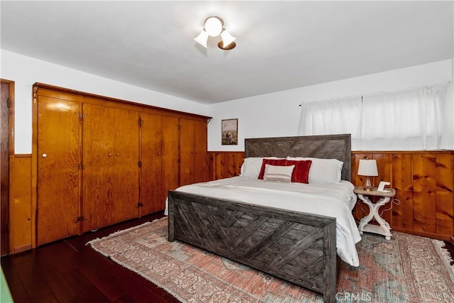 bedroom featuring dark wood-type flooring and wooden walls