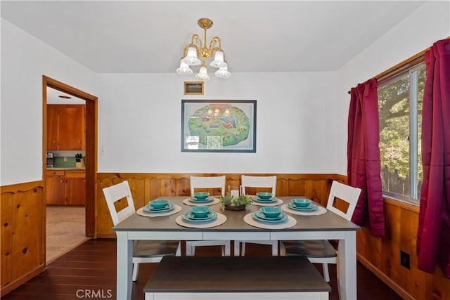 dining area with a notable chandelier, dark hardwood / wood-style floors, and wood walls