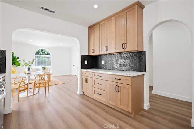 kitchen with light brown cabinetry, backsplash, and light hardwood / wood-style flooring