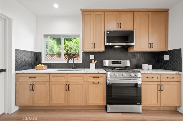 kitchen featuring light brown cabinetry, decorative backsplash, sink, and appliances with stainless steel finishes