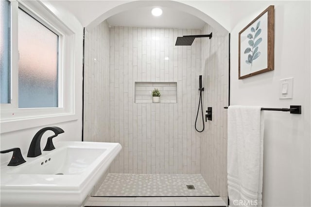 bathroom with tiled shower and sink