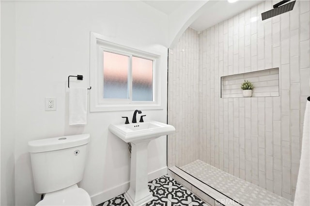 bathroom featuring a tile shower, tile patterned floors, and toilet