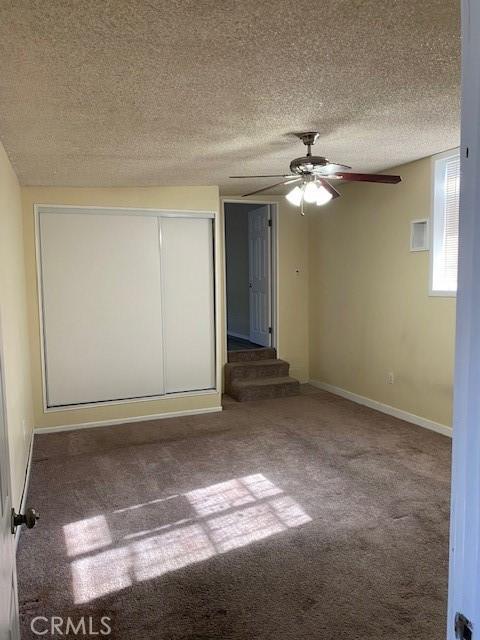 unfurnished room featuring ceiling fan, carpet floors, and a textured ceiling