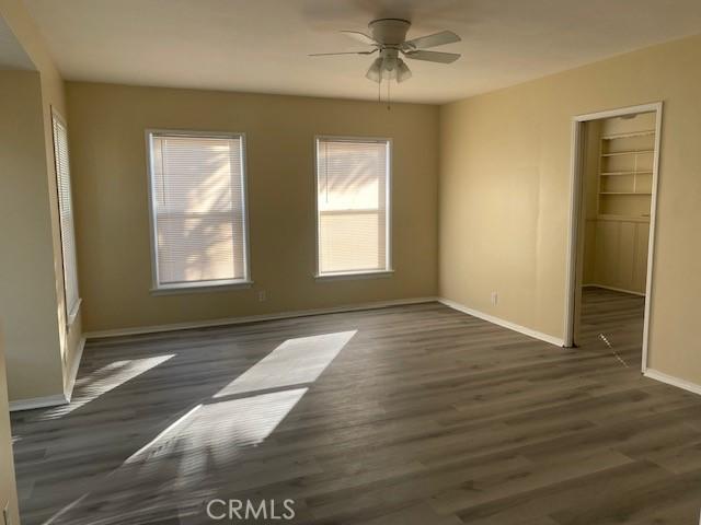 empty room with ceiling fan and dark wood-type flooring