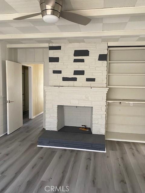 room details featuring a stone fireplace, beamed ceiling, and hardwood / wood-style flooring